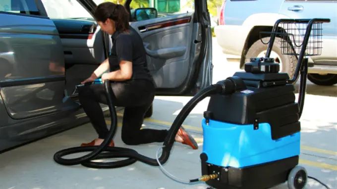 Woman cleaning vehicle with machine